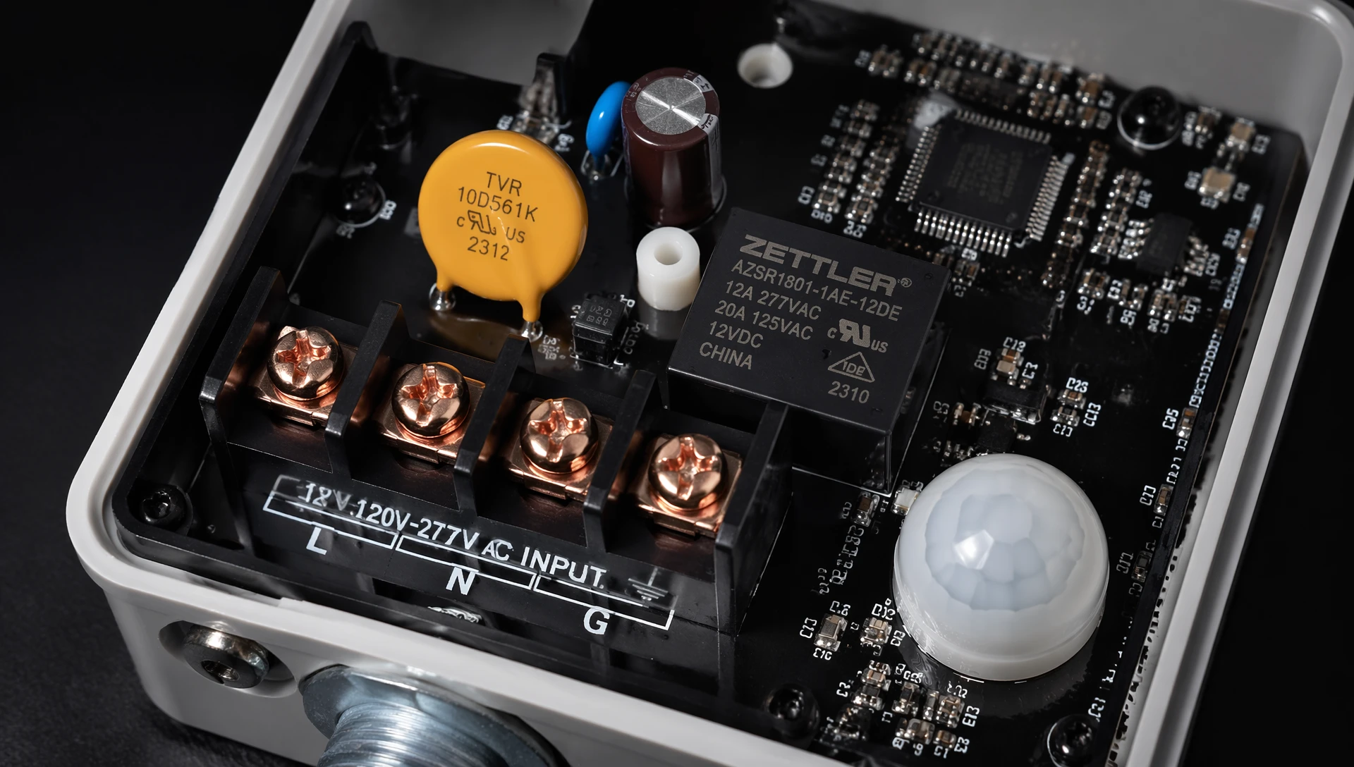 Close-up shot of an industrial hardwired motion sensor internal circuit board featuring universal voltage terminals and surge protection components Close-up shot of an industrial hardwired motion sensor internal circuit board featuring universal voltage terminals and surge protection components